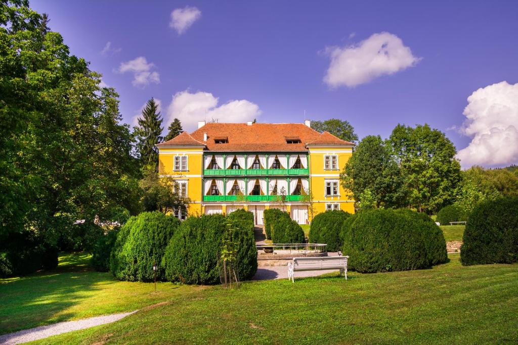 una casa amarilla con un banco en un parque en Zabola Estate - Transylvania, en Zăbala