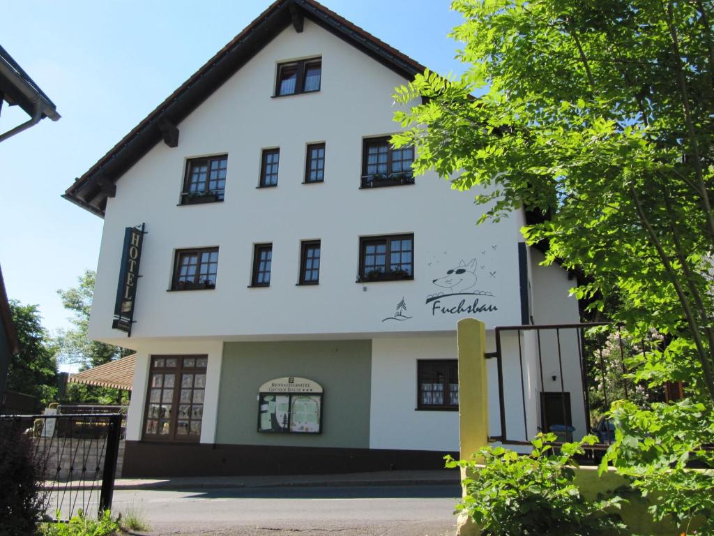 ein weißes Haus mit schwarzen Fenstern in der Unterkunft Rennsteighotel Grüner Baum in Schmiedefeld am Rennsteig