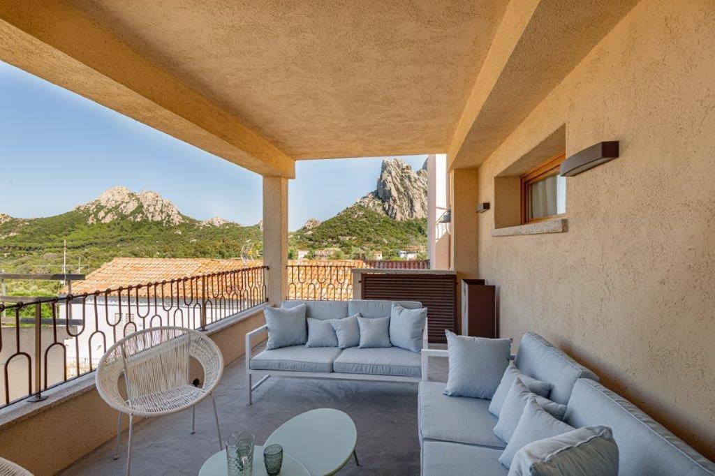 un soggiorno con divani e un balcone con vista sulle montagne. di Appartamento Azzurro a San Pantaleo