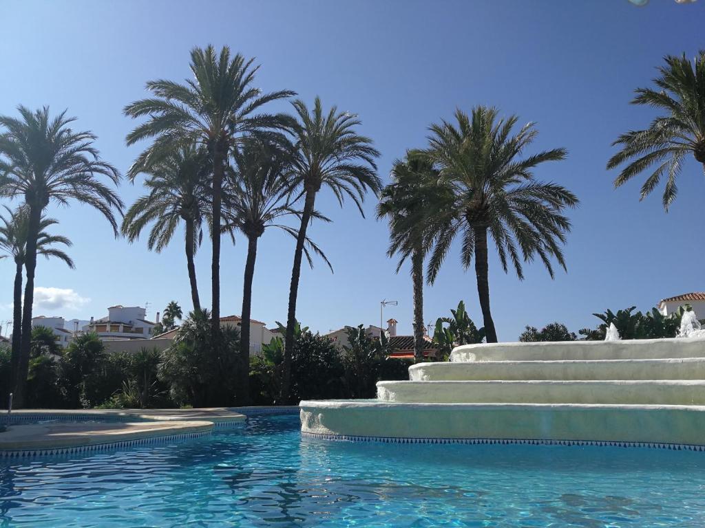 uma piscina com palmeiras ao fundo em Estudio con Piscina, Playa y Wifi em Denia