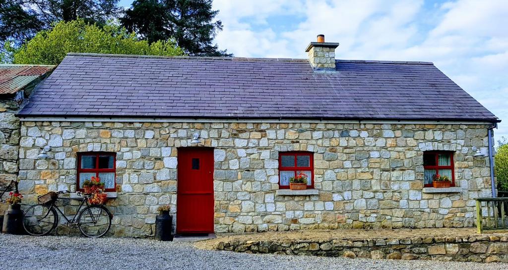 een stenen gebouw met een rode deur en een fiets voor de deur bij Turrock Cottage in Shillelagh