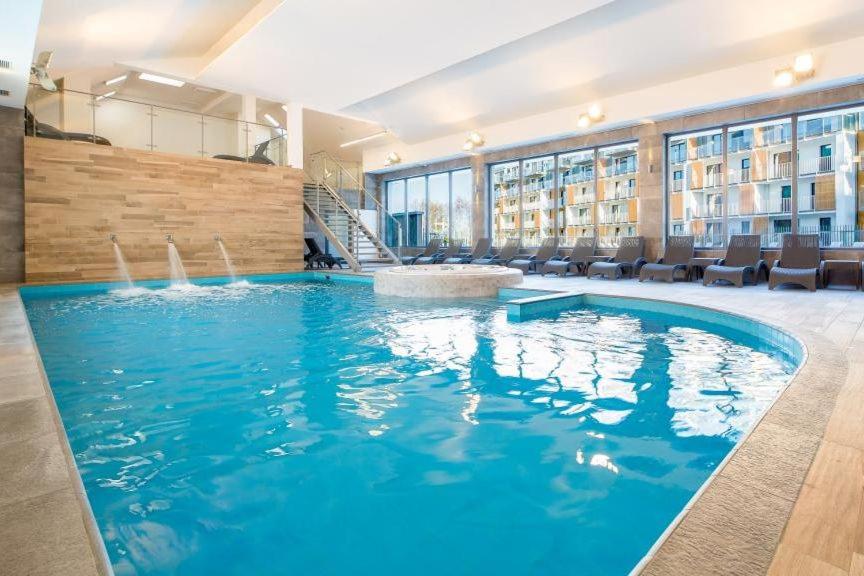 a large swimming pool in a building with chairs at Apartament Siesta Sunny Spa in Kołobrzeg