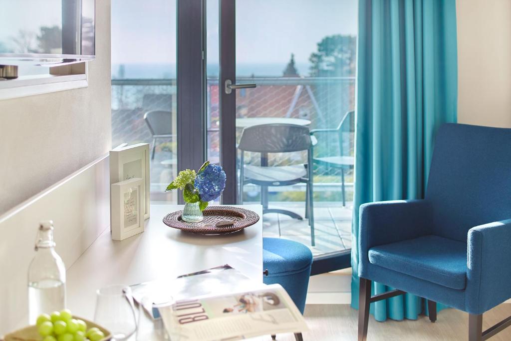 a living room with a table and a chair and a balcony at Familotel Strandkind in Pelzerhaken