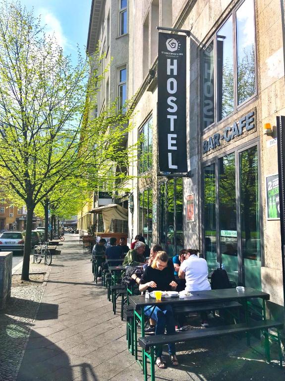 a group of people sitting on benches outside a cafe at St Christopher's Berlin - Alexanderplatz Apartments in Berlin
