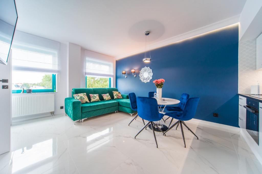 a living room with blue walls and a green couch at Black & White Apartments in Koszalin
