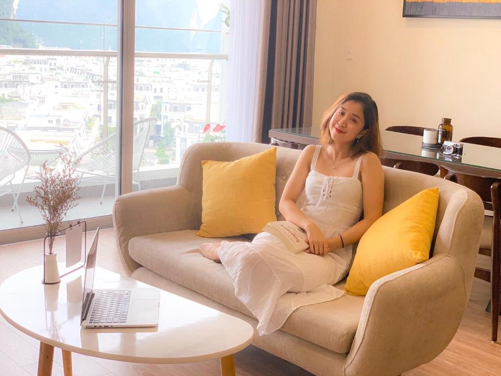 una mujer sentada en un sofá en una sala de estar en BunHomestay SPACIOUS 4 Bedroom CITY&SEA View 1 min walk to SEA, en Ha Long