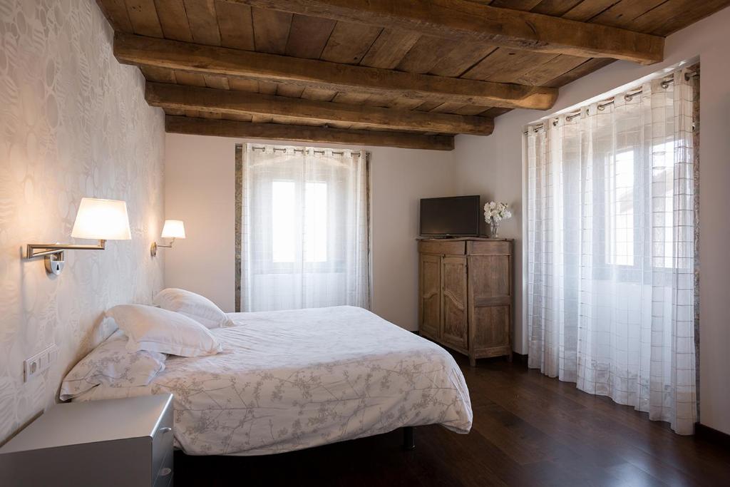 1 dormitorio con 1 cama grande y 2 ventanas en Casa Rural Enea, en Oskotz