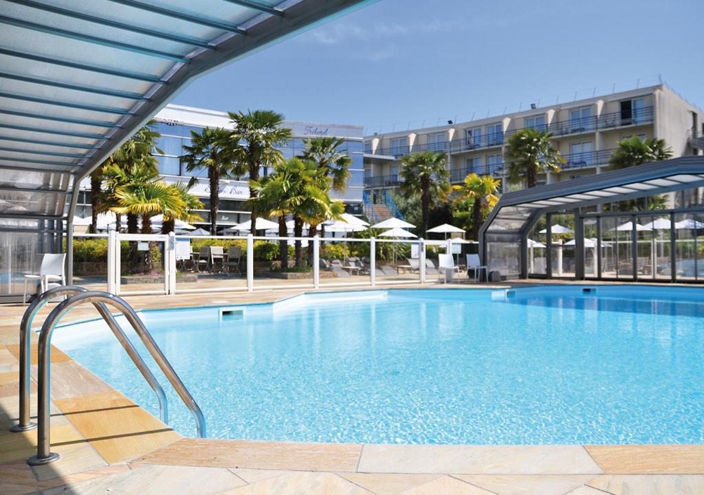 una gran piscina con un edificio en el fondo en Westotel Nantes Atlantique, en La Chapelle-sur-Erdre