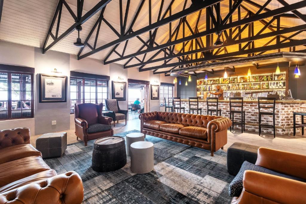 een bibliotheek met leren banken en een bar bij Gondwana Etosha Safari Lodge in Okaukuejo