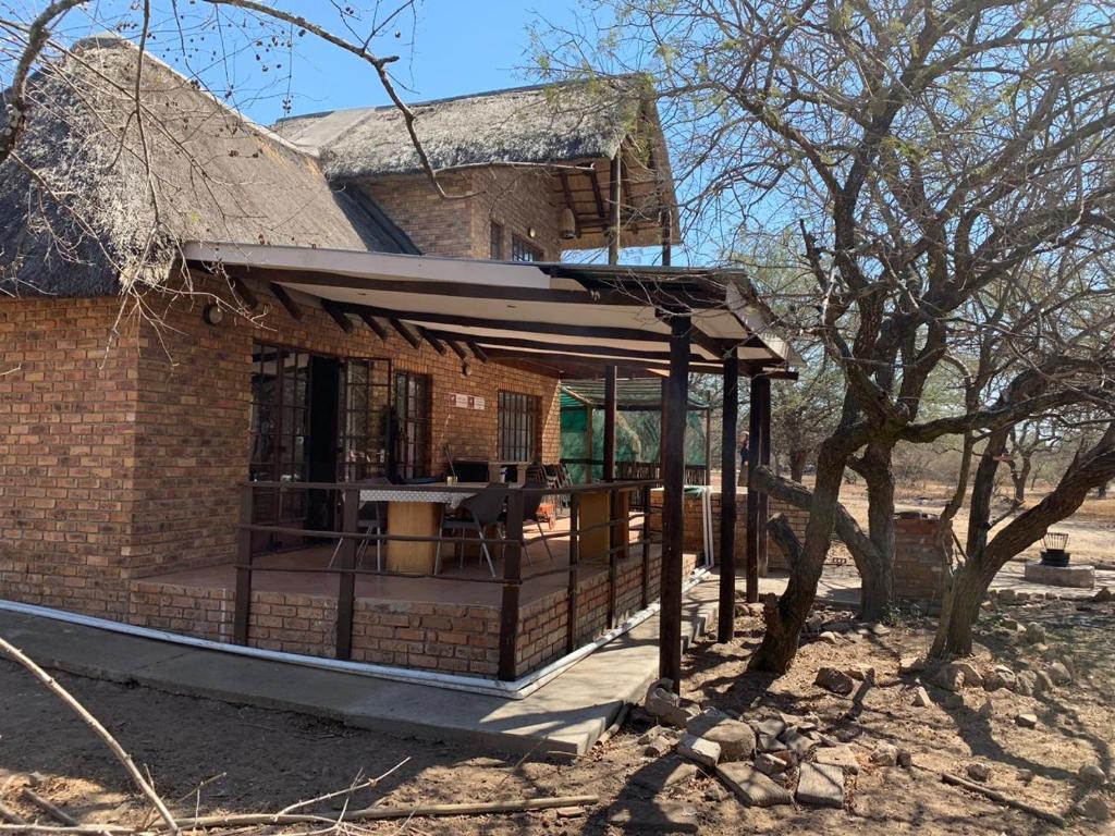 a building with a porch with a table in it at Mopani Villa in Marloth Park
