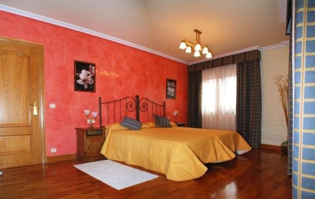 a bedroom with a large bed with red walls at El Encinedo in Genevilla