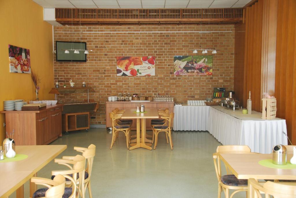 ein Restaurant mit Tischen und Stühlen und einer Ziegelwand in der Unterkunft EVITA Forum Demen in Demen