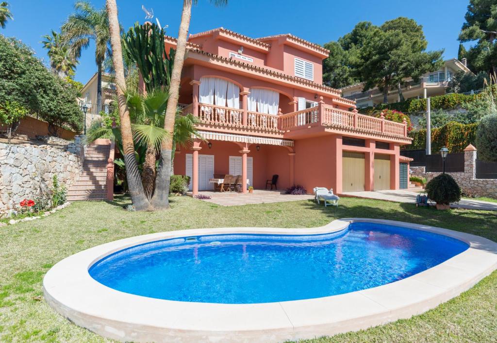 a villa with a swimming pool in front of a house at LU&CIA VILLA CANDADO in Málaga
