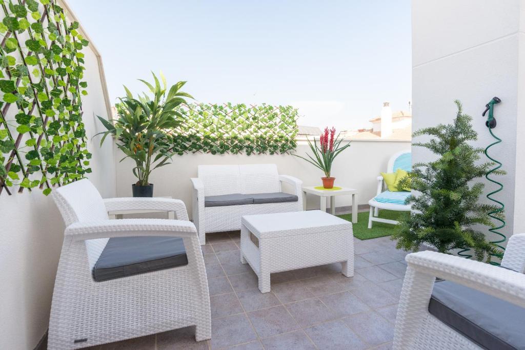 a patio with white chairs and tables and plants at LU&CIA EL CARMEN in M&aacute;laga