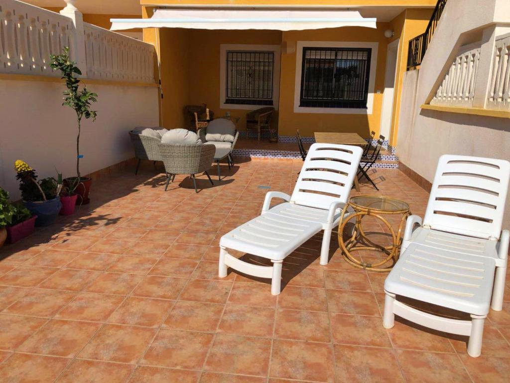 two white chairs sitting on top of a patio at APARTAMENTO CON TERRAZA 50M2，500M A LA PLAYA in Arenales del Sol