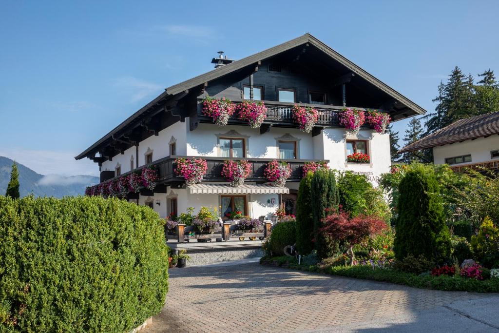 ein weißes Gebäude mit Blumen auf den Balkonen in der Unterkunft Haus Konrad in Reith im Alpbachtal