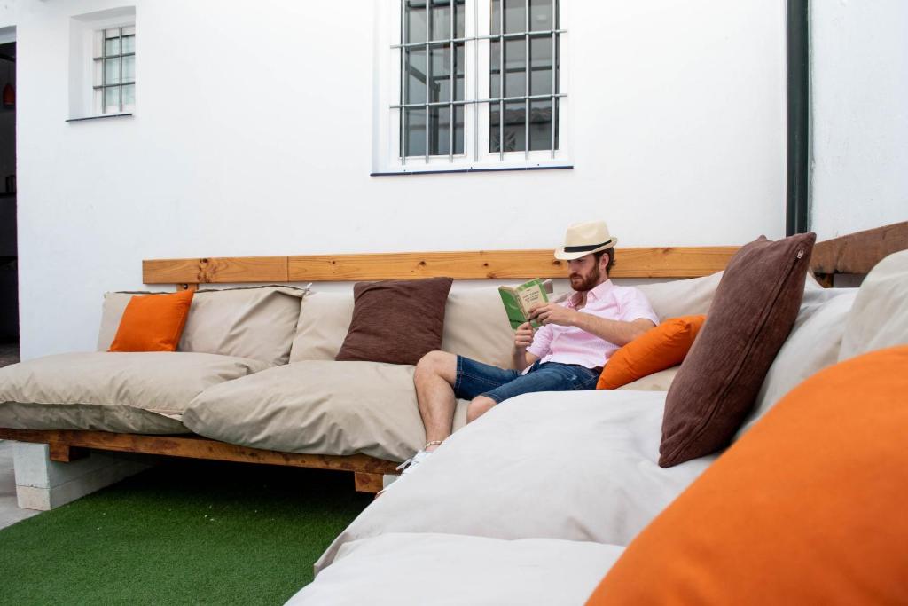 un hombre sentado en un sofá leyendo un libro en Casa Juan Breva en Málaga