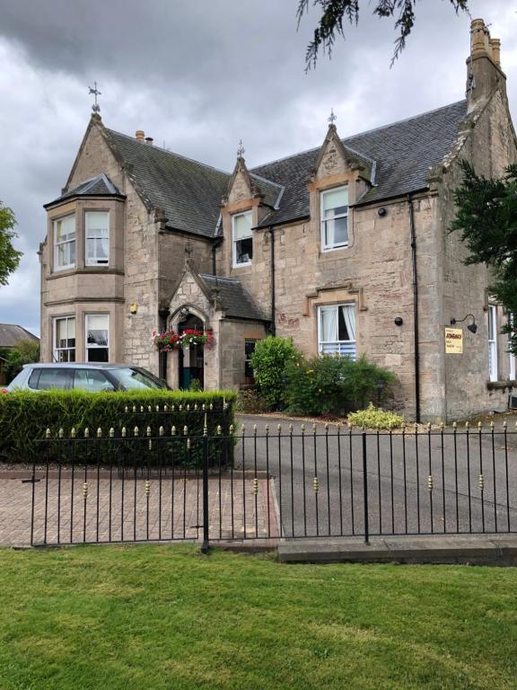 una gran casa de piedra con una valla delante en Ardmeanach, en Inverness