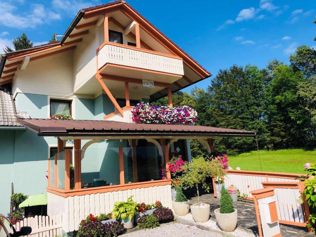 uma casa com uma varanda com flores em Apartma Eržen em Zgornje Gorje