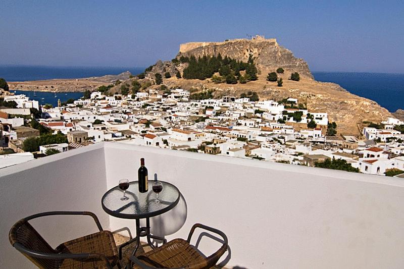 un tavolo e sedie su un balcone con vista sulla città di Lindos Panorama a Líndos