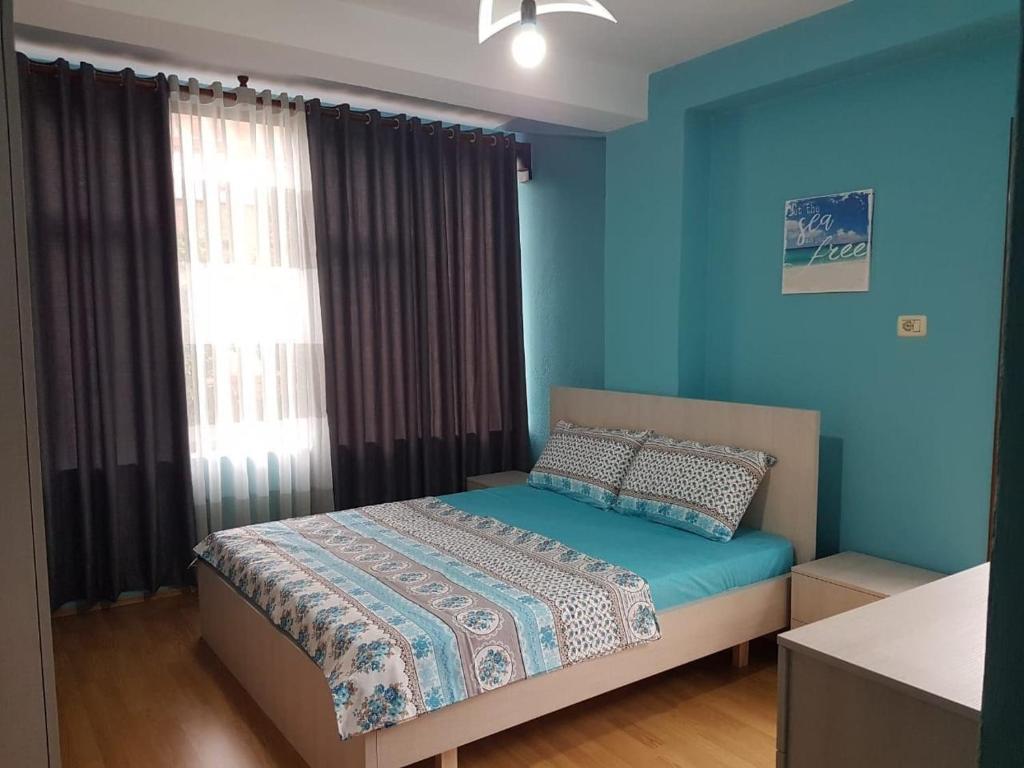 um quarto com uma cama com paredes azuis e uma janela em Lovely Apt at the heart of the city&near the lake em Pogradec