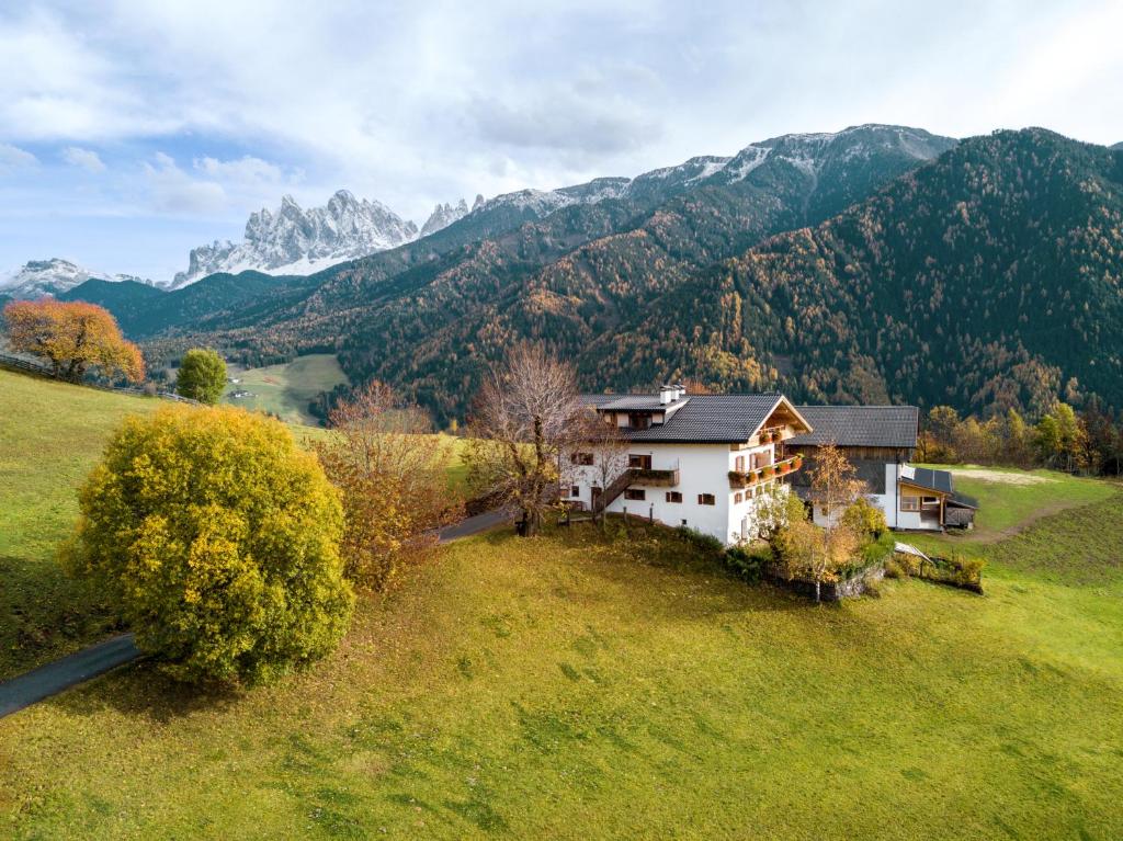 una casa en un campo con montañas en el fondo en Gasleidhof, en Funes