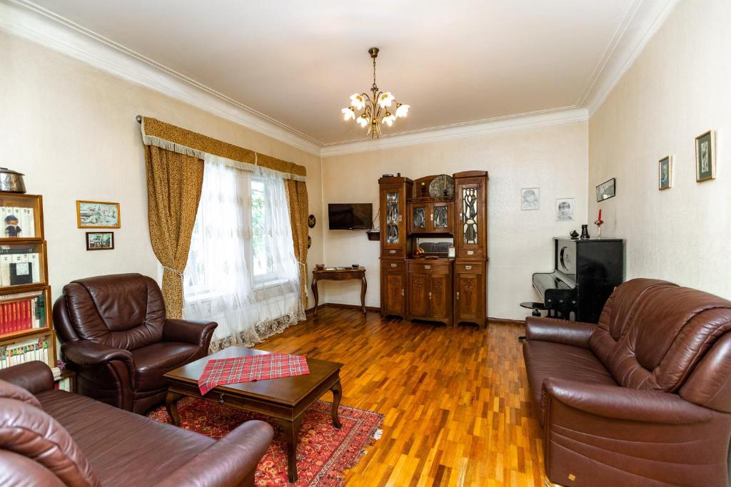 uma sala de estar com sofás de couro e uma televisão em Vere House em Tbilisi