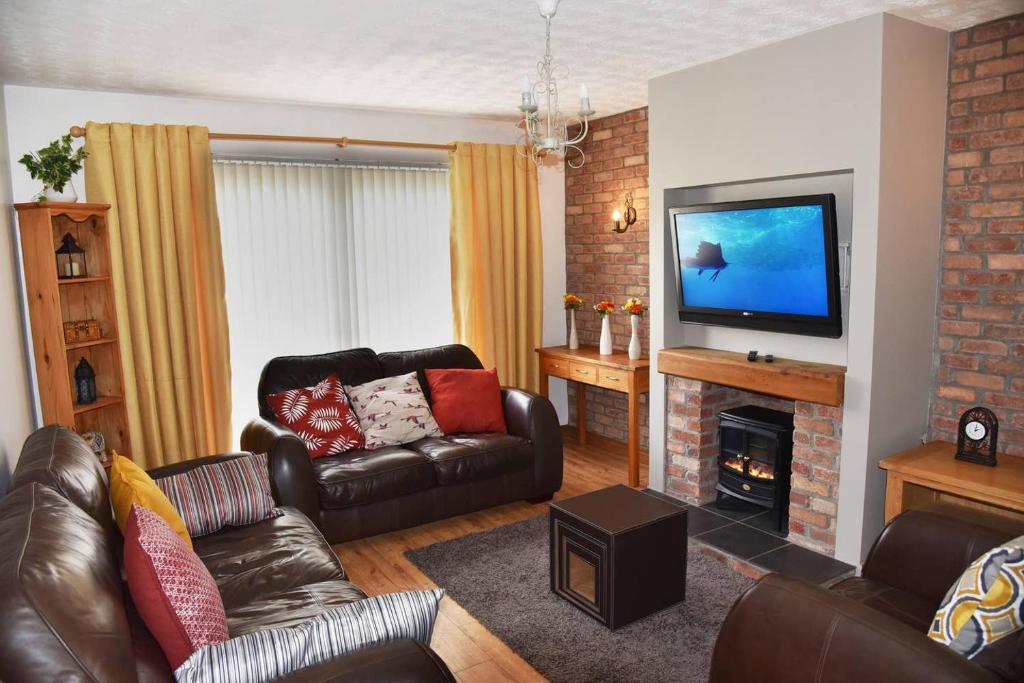 ein Wohnzimmer mit Ledermöbeln und einem Flachbild-TV in der Unterkunft ADAIR HOUSE in Ballymena