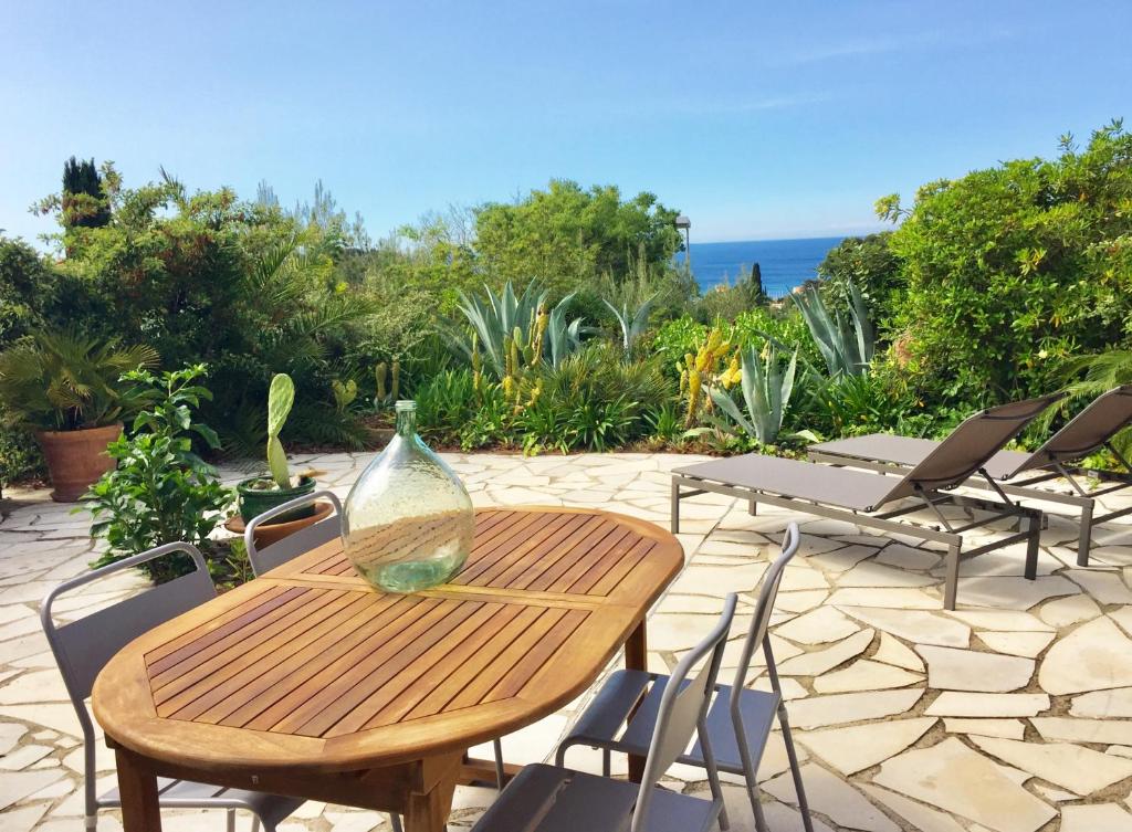 une table en bois avec des chaises et un vase en verre. dans l'établissement Calanque, à Cassis