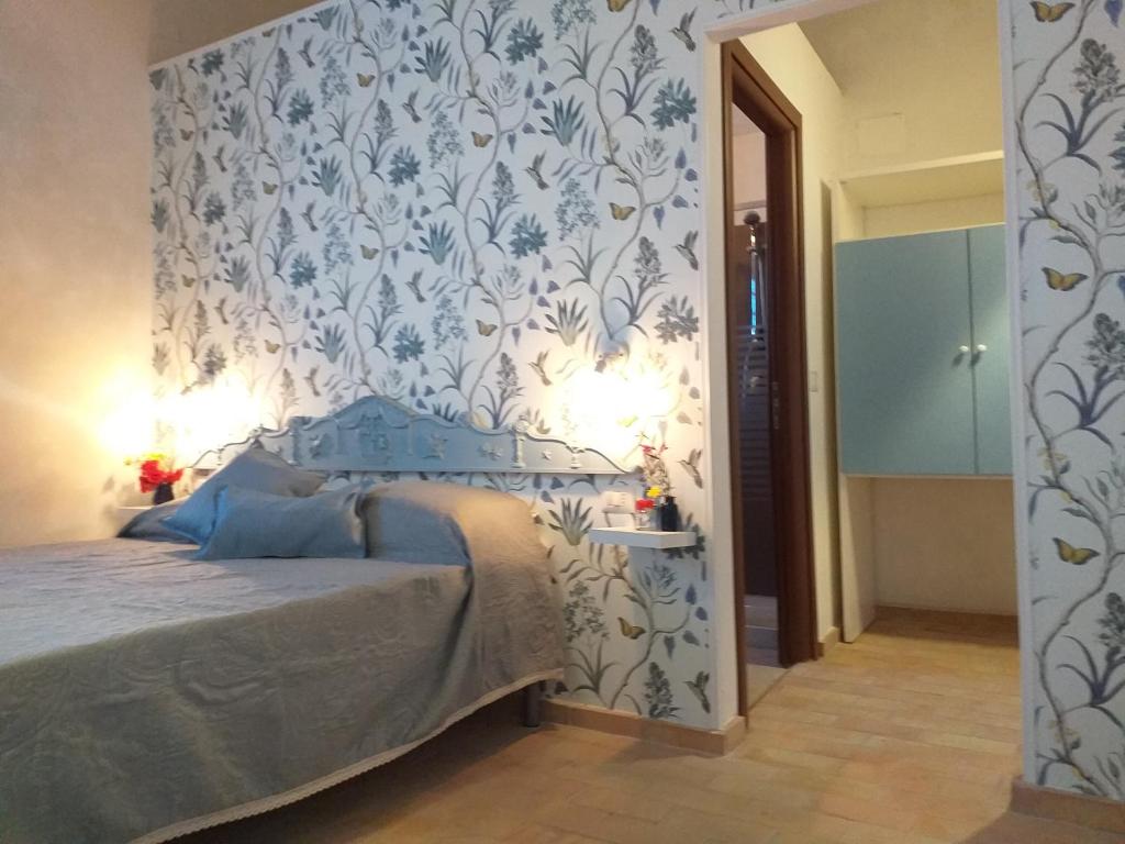 Schlafzimmer mit einem Bett mit einer blauen und weißen Tapete in der Unterkunft Gibbesi country farm piccolo cottage in Naro