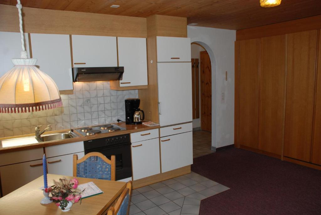 a kitchen with white cabinets and a table and a sink at Appartment & Taxi Tirana in Samnaun