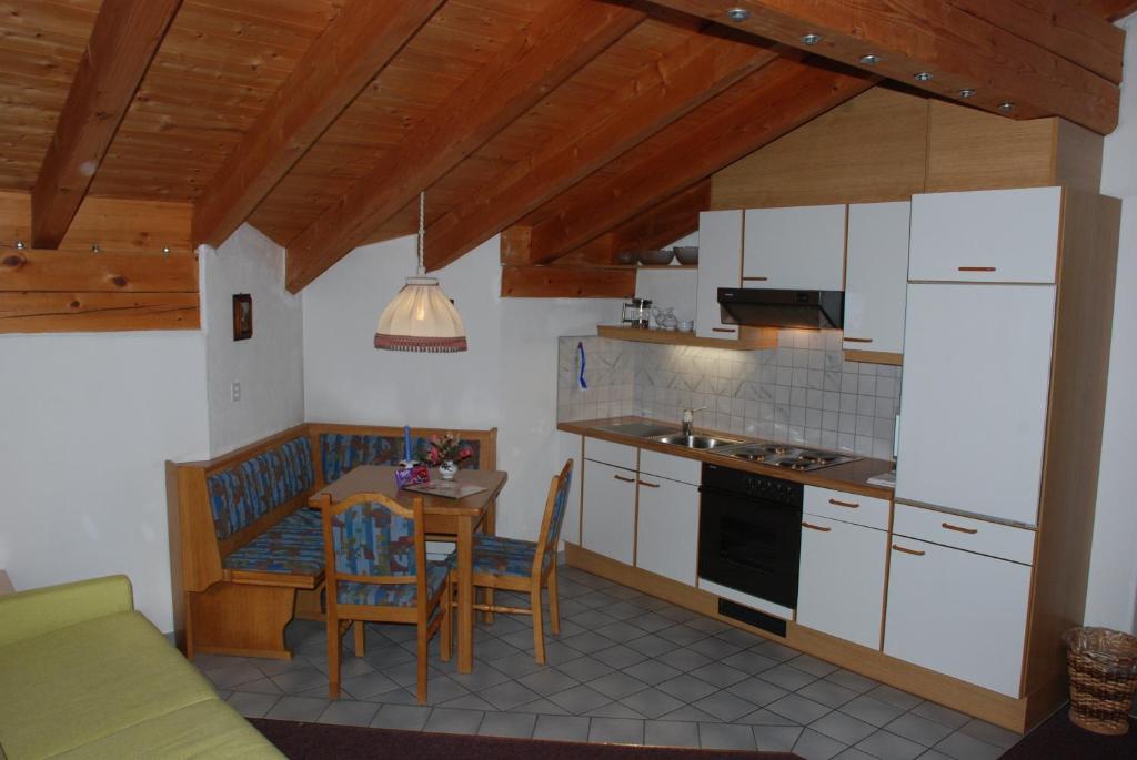 a kitchen with white cabinets and a table with chairs at Appartment & Taxi Tirana in Samnaun