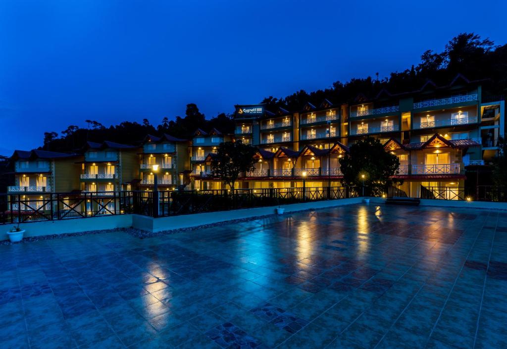um hotel à noite com uma piscina em frente em Cygnett Resort Mountain Breeze em Nainital