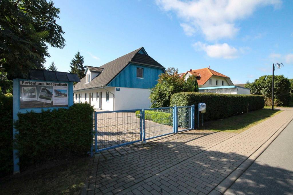 a fence in front of a house with a blue building at Weststrandläufer in Wieck