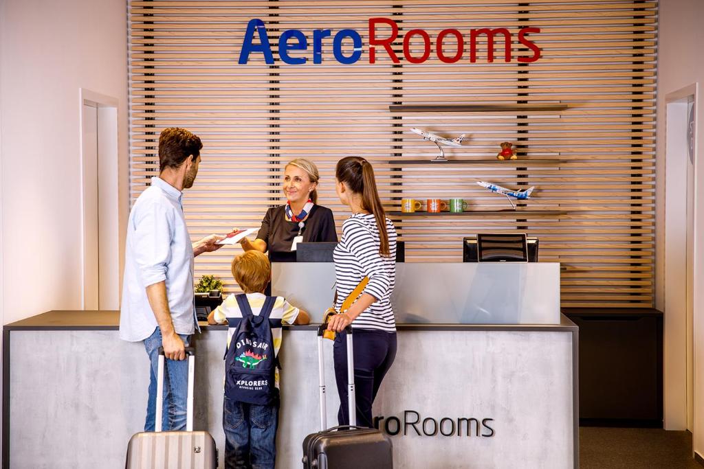 a group of people standing at a reception counter with luggage at AeroRooms in Prague