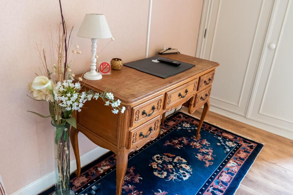 a wooden desk with a lamp and a vase of flowers at B&B El Tyu in Écaussinnes-dʼEnghien