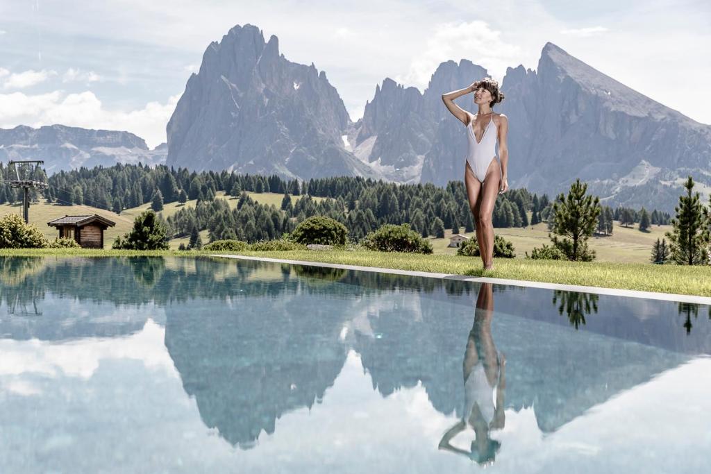 una donna in bikini in piedi accanto alla piscina di Sporthotel Sonne ad Alpe di Siusi