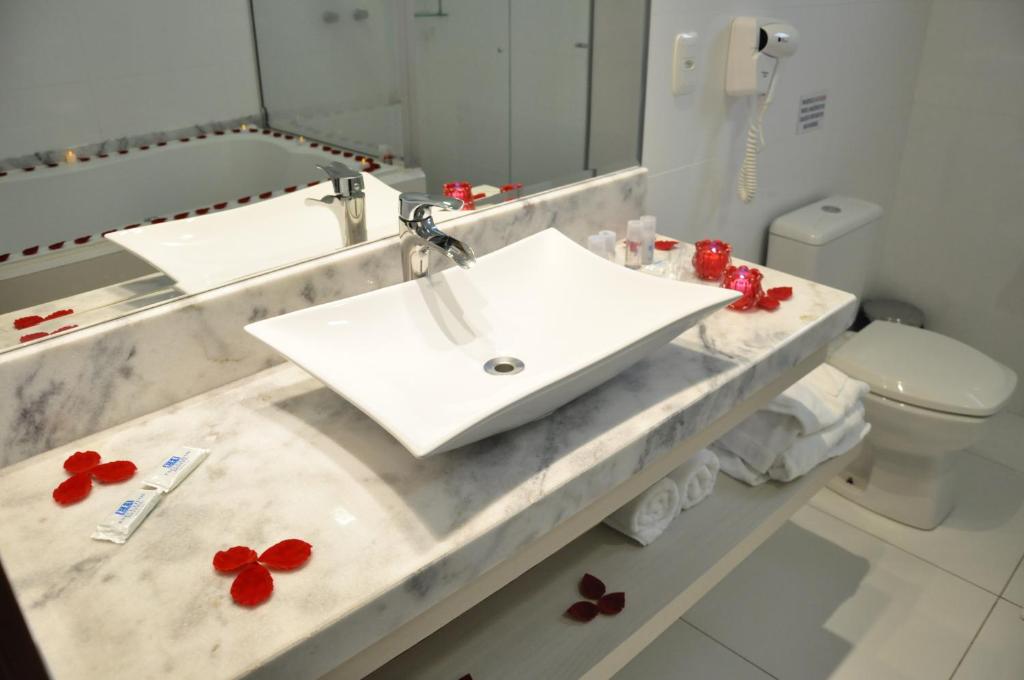 uma casa de banho com um lavatório com flores vermelhas em Executivos Hotel em Cruz Alta