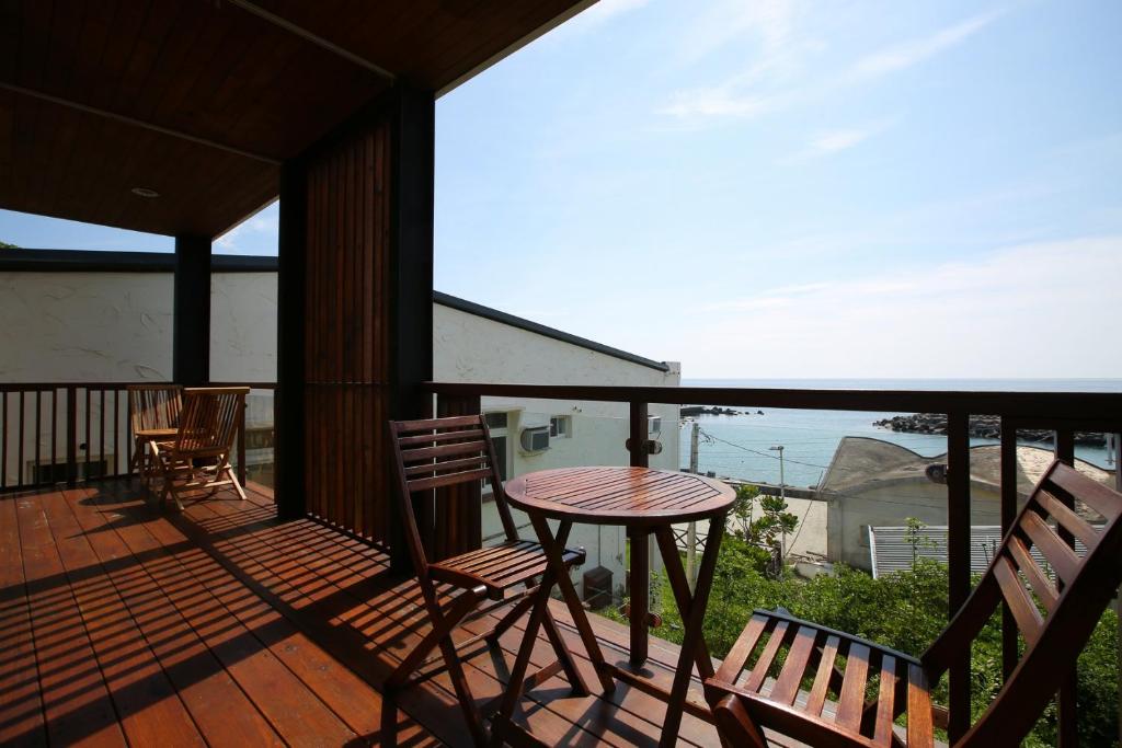 a balcony with a table and chairs and a view of the ocean at Mama Tian Homestay in Xiaoliuqiu