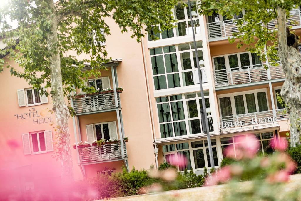 un edificio rosa con balcones y árboles en Hotel Heide Park, en Ora - Auer