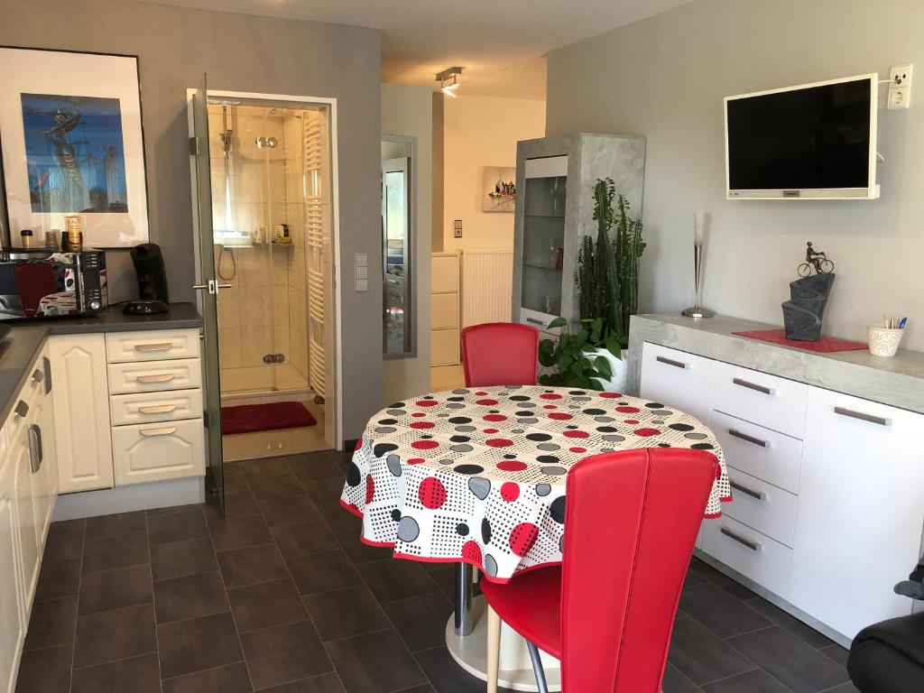 a kitchen with a table and red chairs in a kitchen at VIP Appartement in Mahlberg