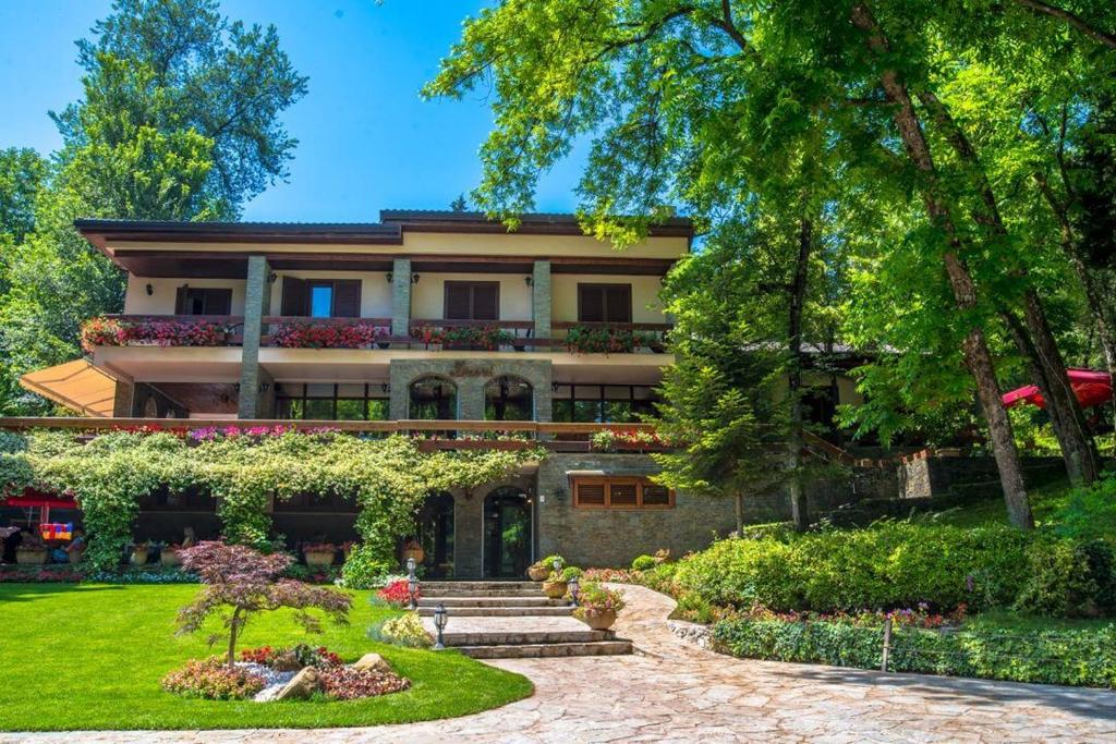 une grande maison avec un jardin en face de celle-ci dans l'établissement Hotel Restaurant Dreri, à Tirana