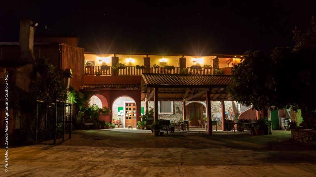 a building with a balcony and a patio at night at Agriturismo Costiolu in Nuoro