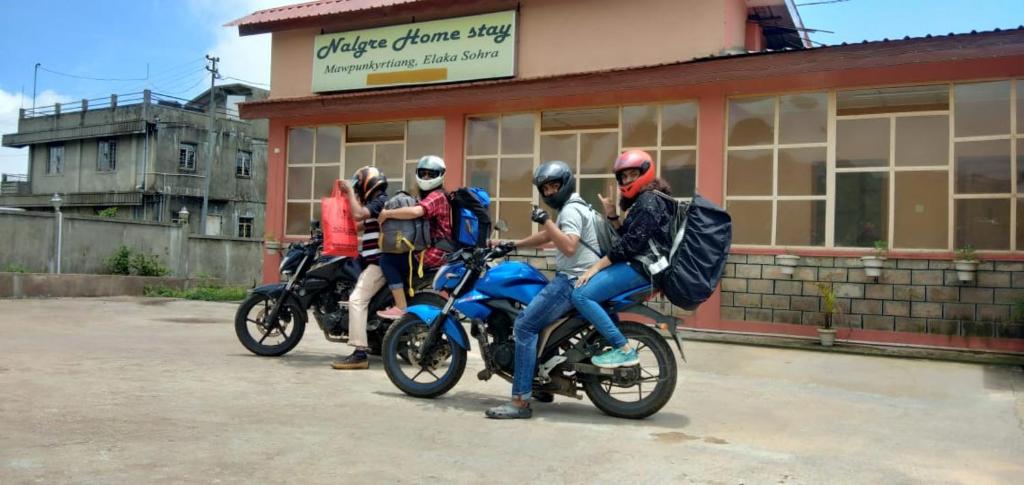 un grupo de personas en motocicleta frente a una tienda en Nalgre Homestay, en Cherrapunji