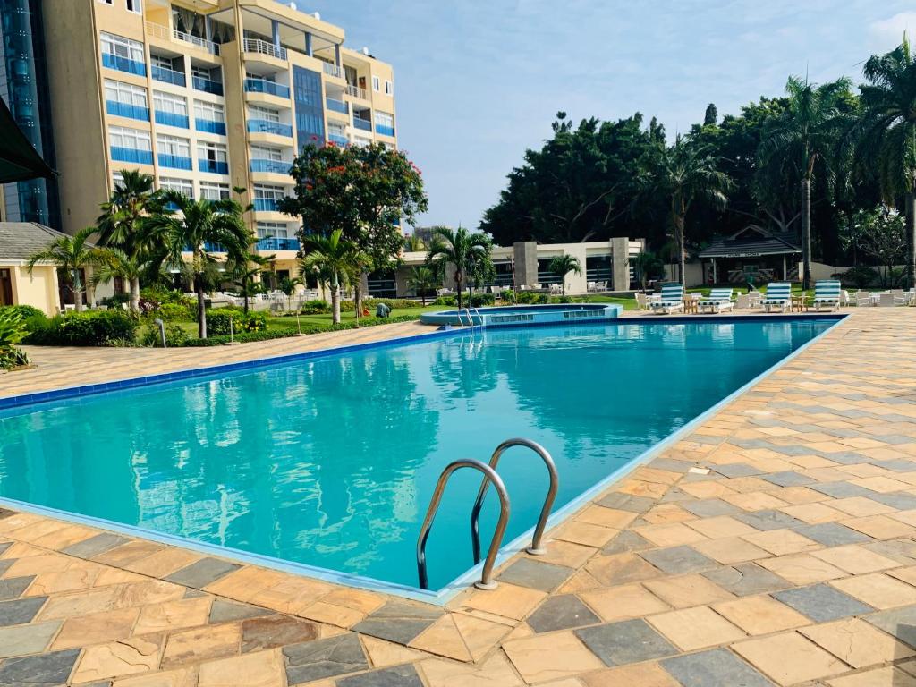 ein Pool in einem Resort mit einem Hotel im Hintergrund in der Unterkunft Tanga Beach Resort & Spa in Tanga