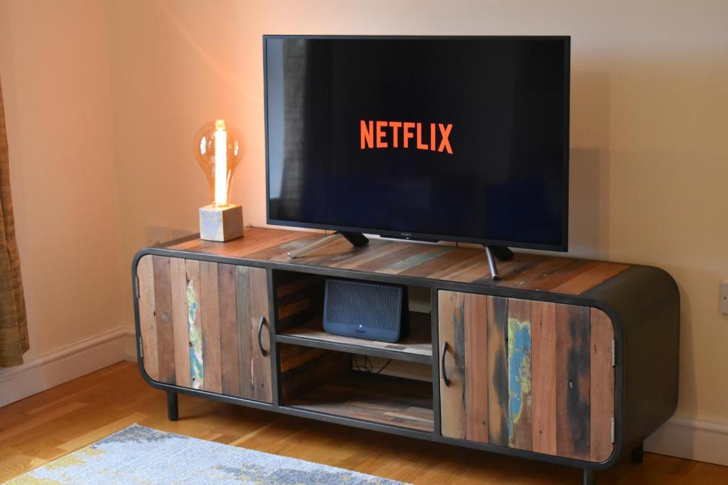 a tv on top of a wooden entertainment center at Urban Nest @Eastwater in Peterborough