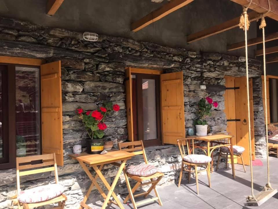 a patio with wooden tables and chairs and a stone wall at Sno House in Kazbeg in Sno