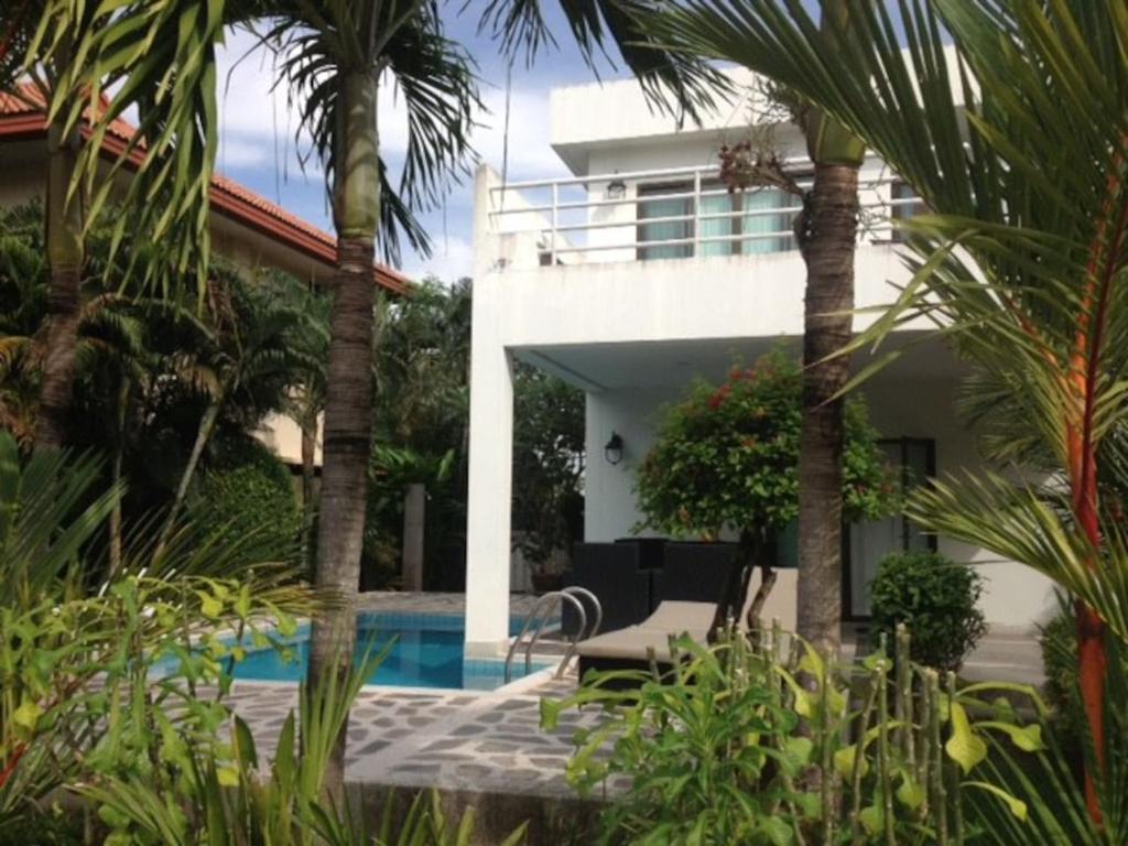 a house with a swimming pool and palm trees at Mae Phim -Beachfront living in a villa with a private pool ! in Ban Tha Fat