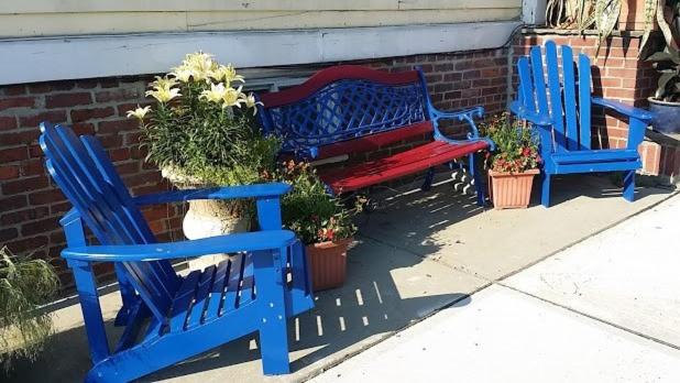 three blue benches sitting next to a brick wall with potted plants at Burbank Rose Inn Bed & Breakfast in Newport