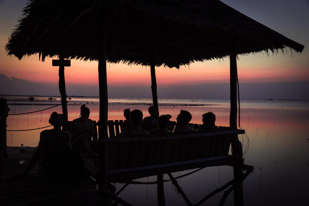 een groep mensen die op een bank zitten te kijken naar de zonsondergang bij TRC Bintan Resort in Sebungsungai